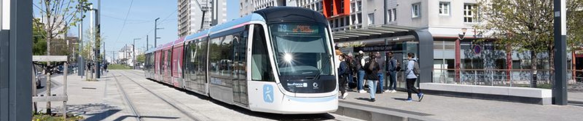 Un tram dans son couloir et des immeubles au fond