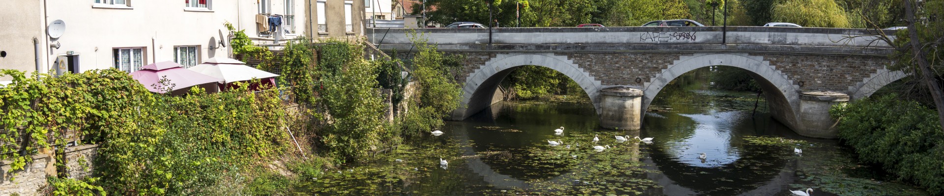 Un pont sur une rivière, des maisons et des arbres au fond