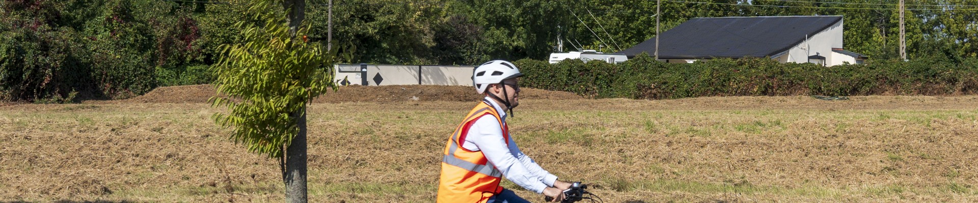 une personne à vélo sur une route bordée d'espaces verts