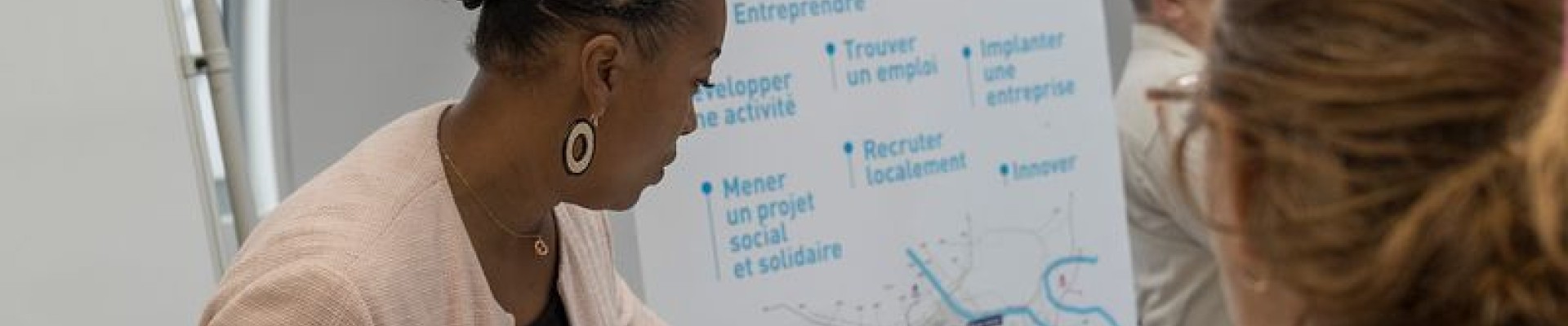 Une conseillère montre le plan du Grand Orly avec les infos emploi