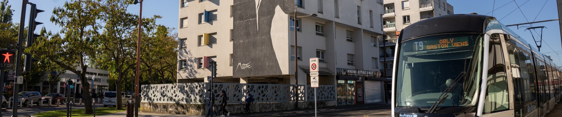 Un tram devant un immeuble décoré par un graph Street Art