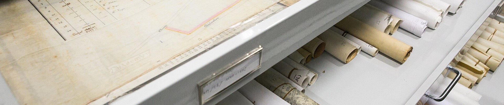 Cartes et rouleaux de documents anciens rangés dans des tiroirs