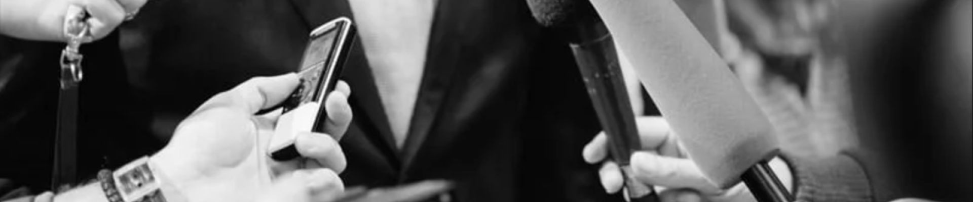 Photo noir et blanc de micros tendus vers quelqu'un dont on ne voit pas le visage