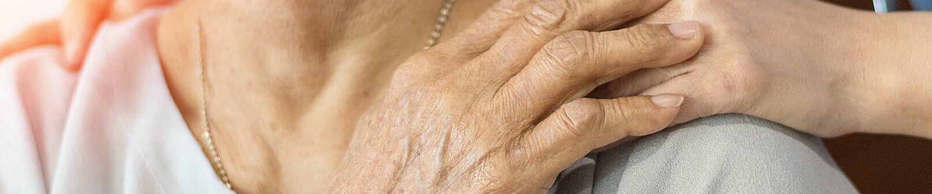 Main d'une personne âgée posée sur celle de son aidant