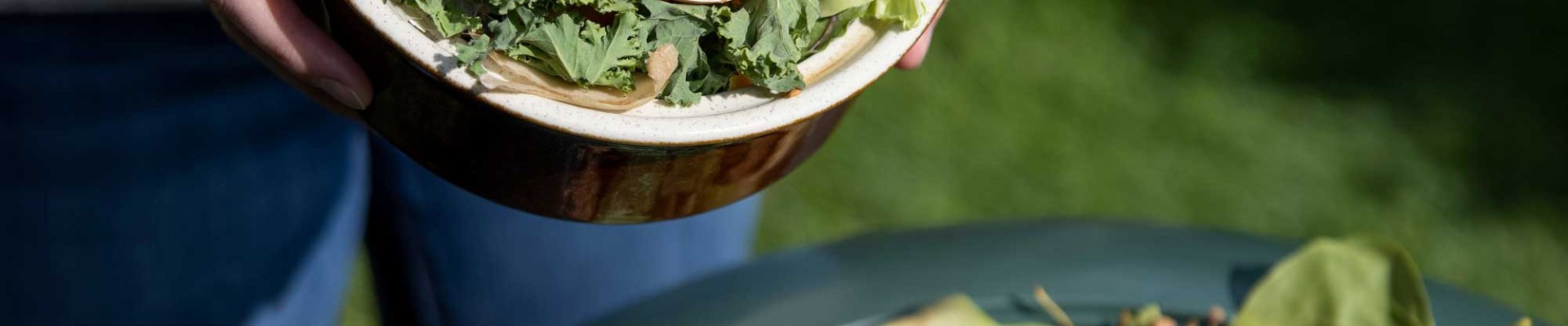 Mains déposant des épluchures dans un composteur