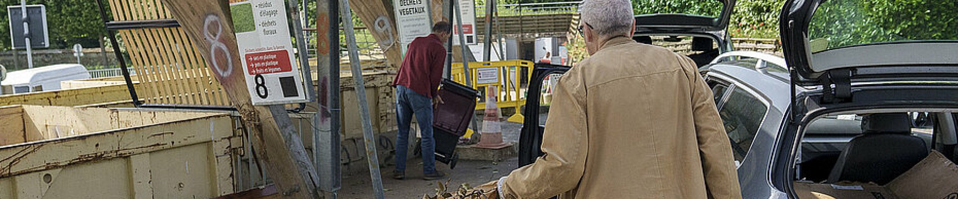 Une personne de dos apporte des sacs de déchets