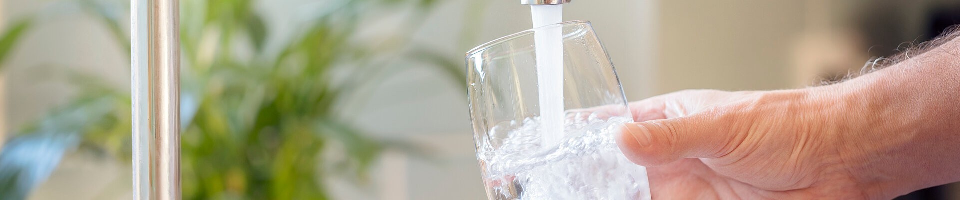 De l'eau coule du robinet dans un verre