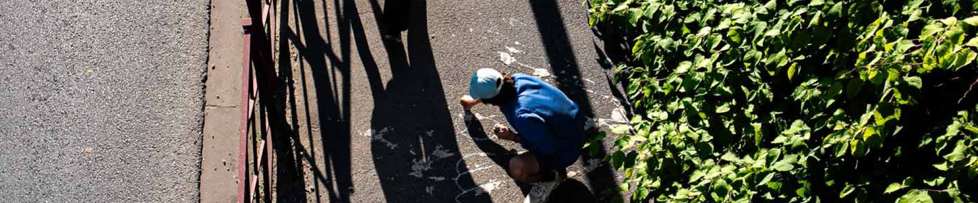 Vue aérienne de l'artiste Malo Patron écrivant sur un trottoir ses textes sur la Bièvre