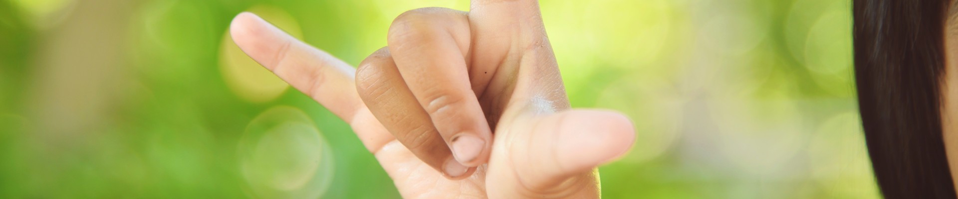 Une main mime un lapin sur fond vert