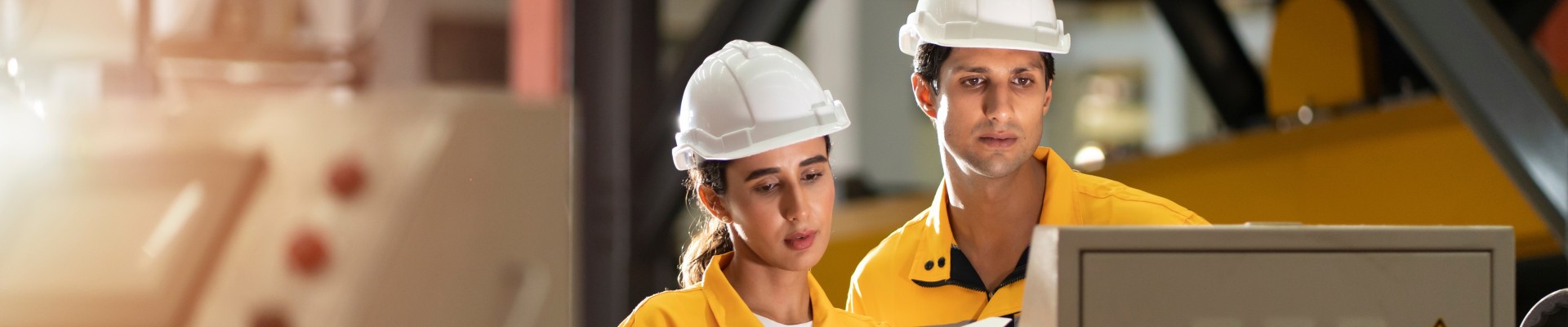 2 personnes dont une jeune portant des casques de chantier regardent un écran