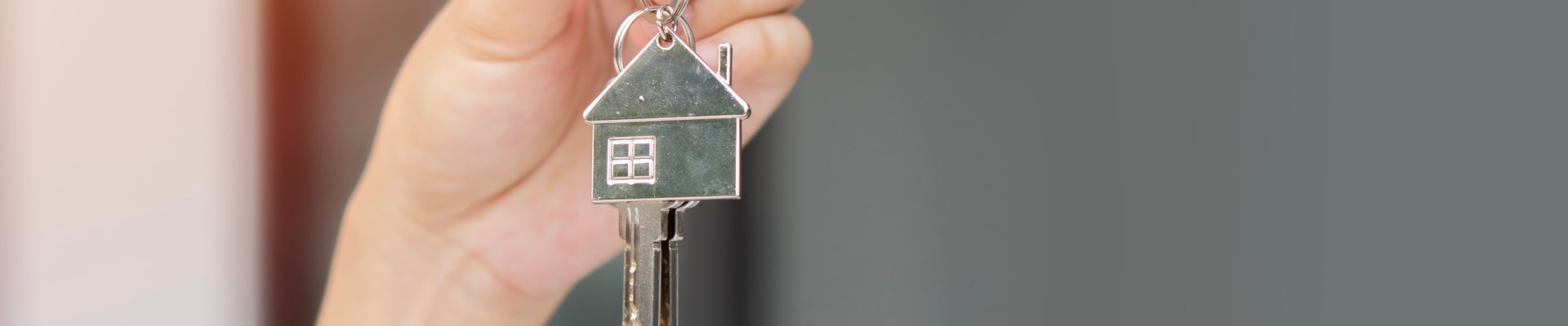 Une main tient une clé et un porte-clé en forme de maison