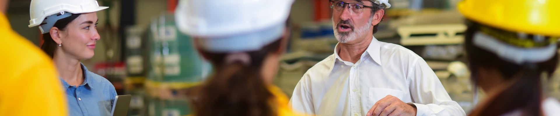 Des personnes portant un casque de chantier écoutent une personne avec des lunettes et un casque