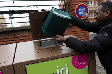 Un homme jette ses restes alimentaires dans des abris-bac de collecte des biodéchets