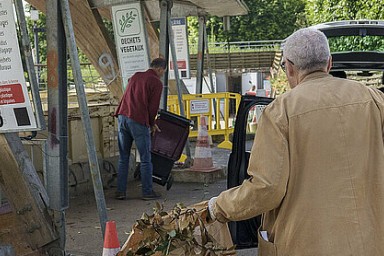 Une personne de dos apporte des sacs de déchets