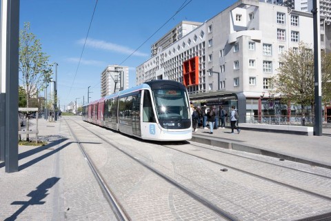 Un tram dans son couloir et des immeubles au fond