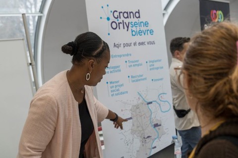 Une conseillère montre le plan du Grand Orly avec les infos emploi