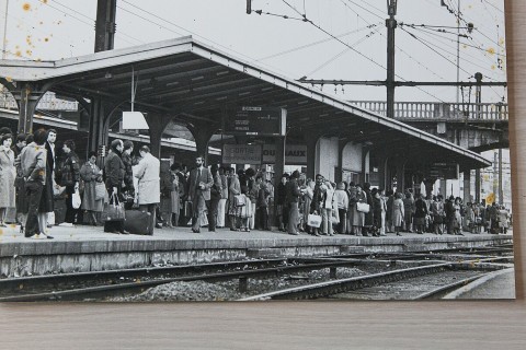 Photo en noir et blanc, tachée, représentant des voyageurs sur un quai de gare