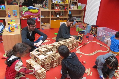Enfants et deux adulates jouant à un jeu de construction