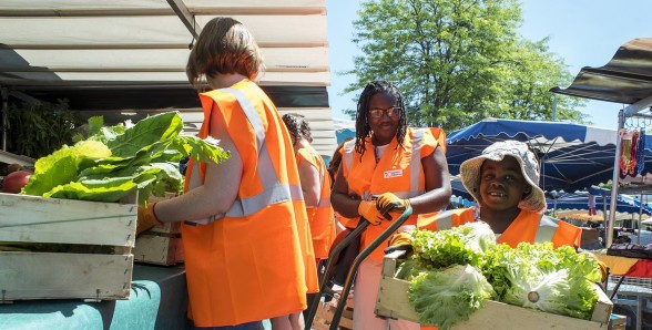Des bénévoles en gilet orange récupèrent des salades sur un stand - Agrandir l'image, fenêtre modale