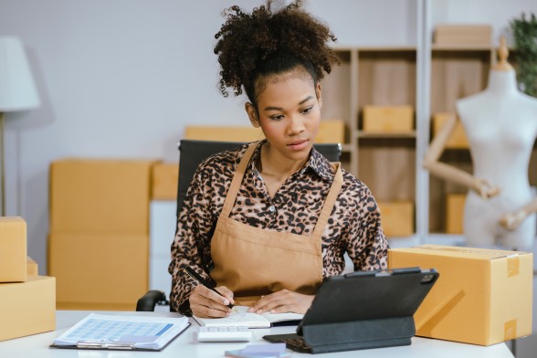 Une femme travaille devant un portable et prend des notes